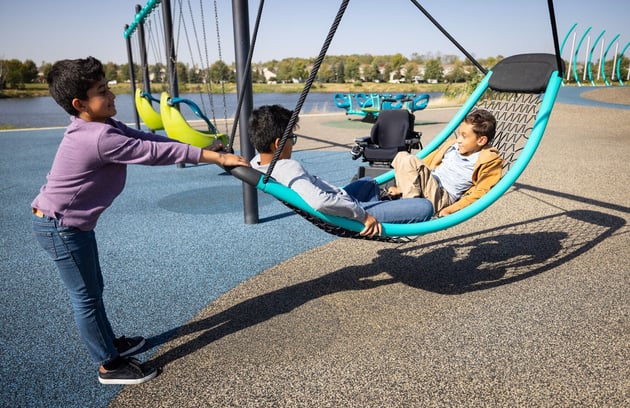 Children laughing and playing together on the Flexx™ Swing, showcasing inclusive design that enables shared play experiences in motion