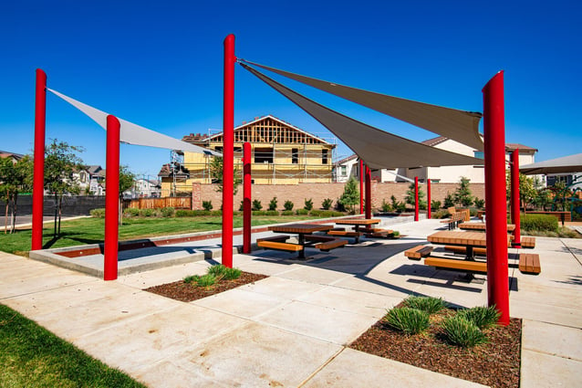 Fabric shade structures in a park create a cool, inviting space for picnics and leisure activities.