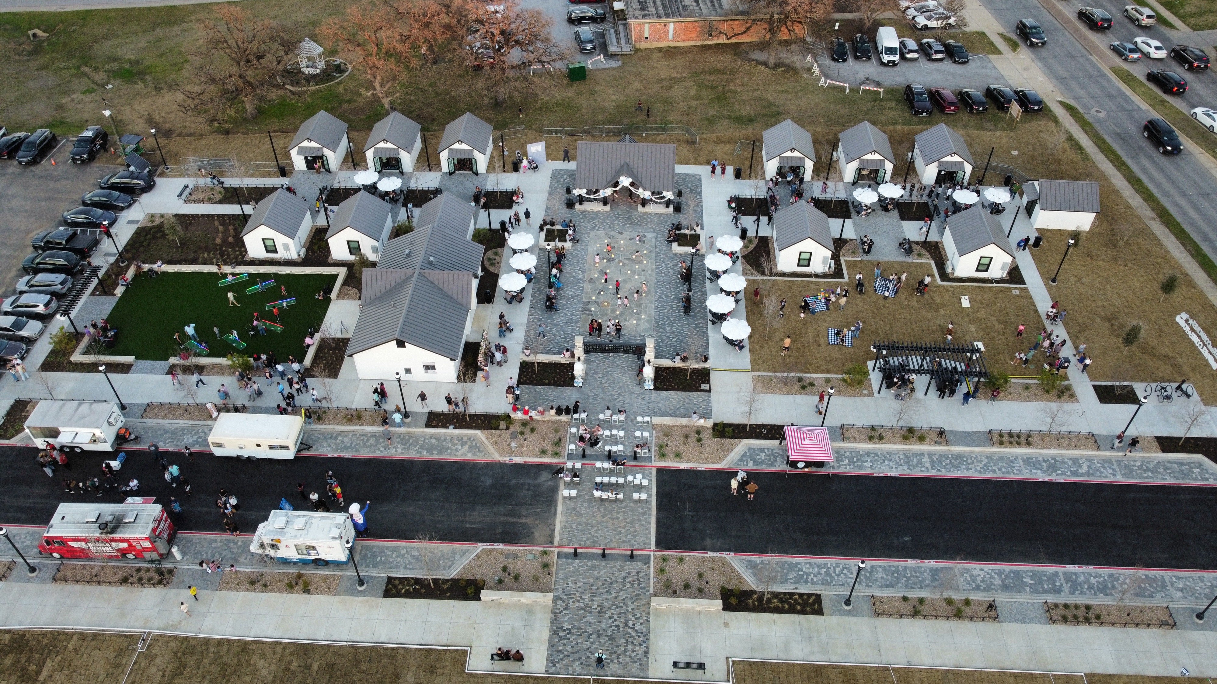 Aerial view of children playing in the Geyer Commons splash pad with programmable water jets and a shaded pavilion in Mansfield, Texas.