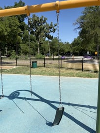 A desolate scene at Dream Park showing a broken swing hanging limply from its chains.